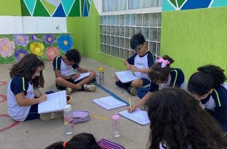 Alunos do Colégio Gênesis estudando ao ar livre no pátio da escola